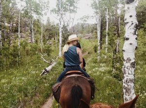 Guests ride between aspen trees