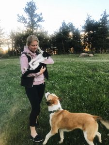 A woman holds a cat and looks at her dog