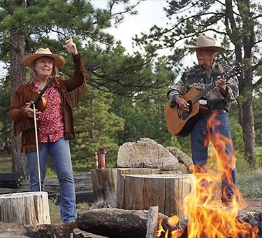 Amy and Lars perform by the campfire.