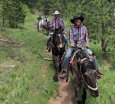 Two wranglers smile for a picture while leading a trail ride.